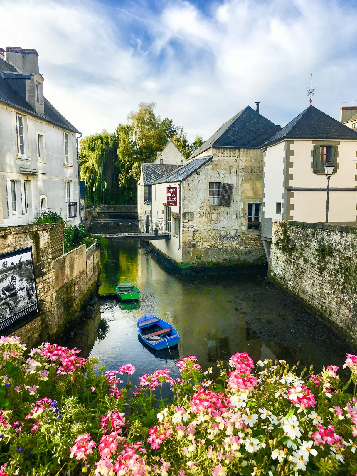 Small boats along a flower-lined canal in the old center of Bayeux