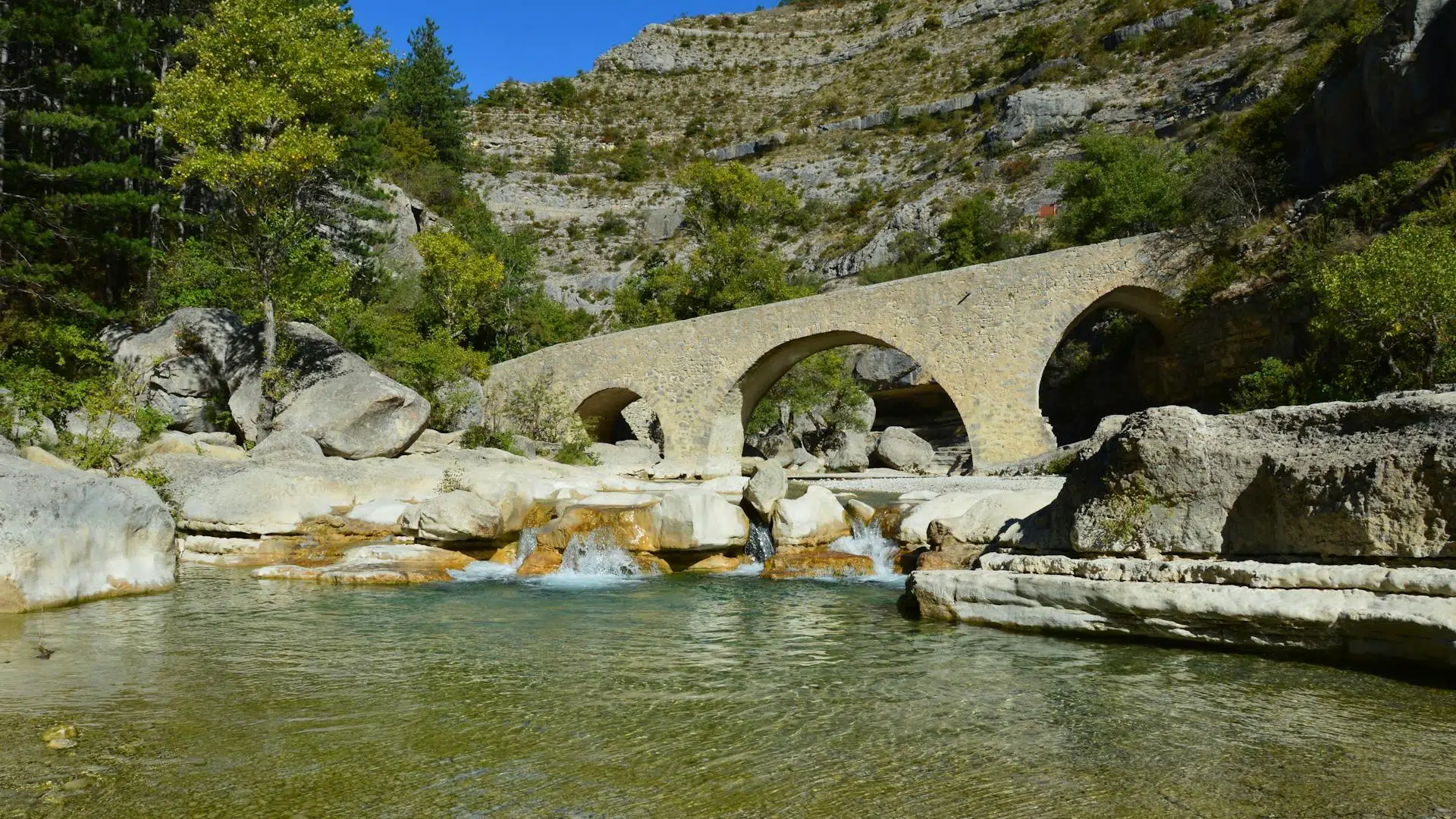 A stone bridge over clear water in the Gorges de la Méouge