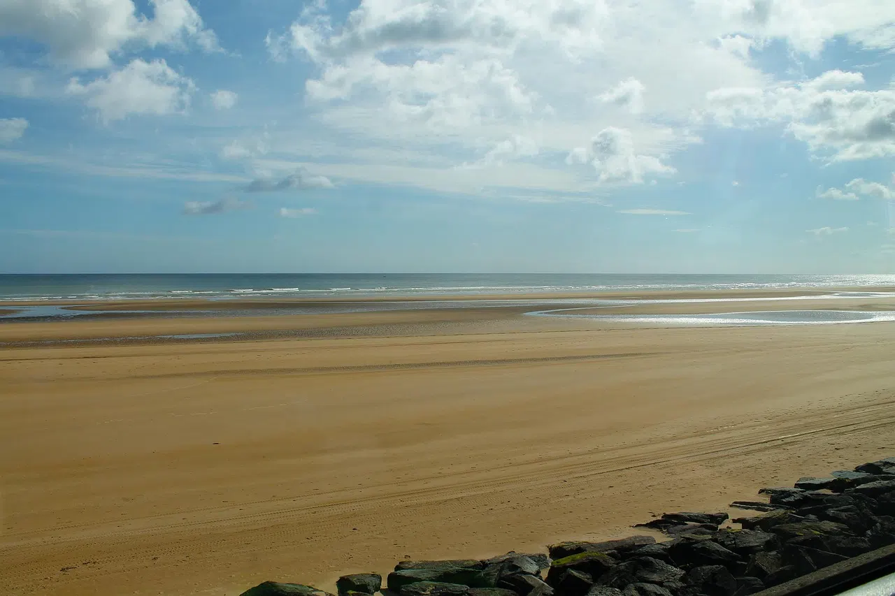 Juno Beach at low tide under a wide Norman sky