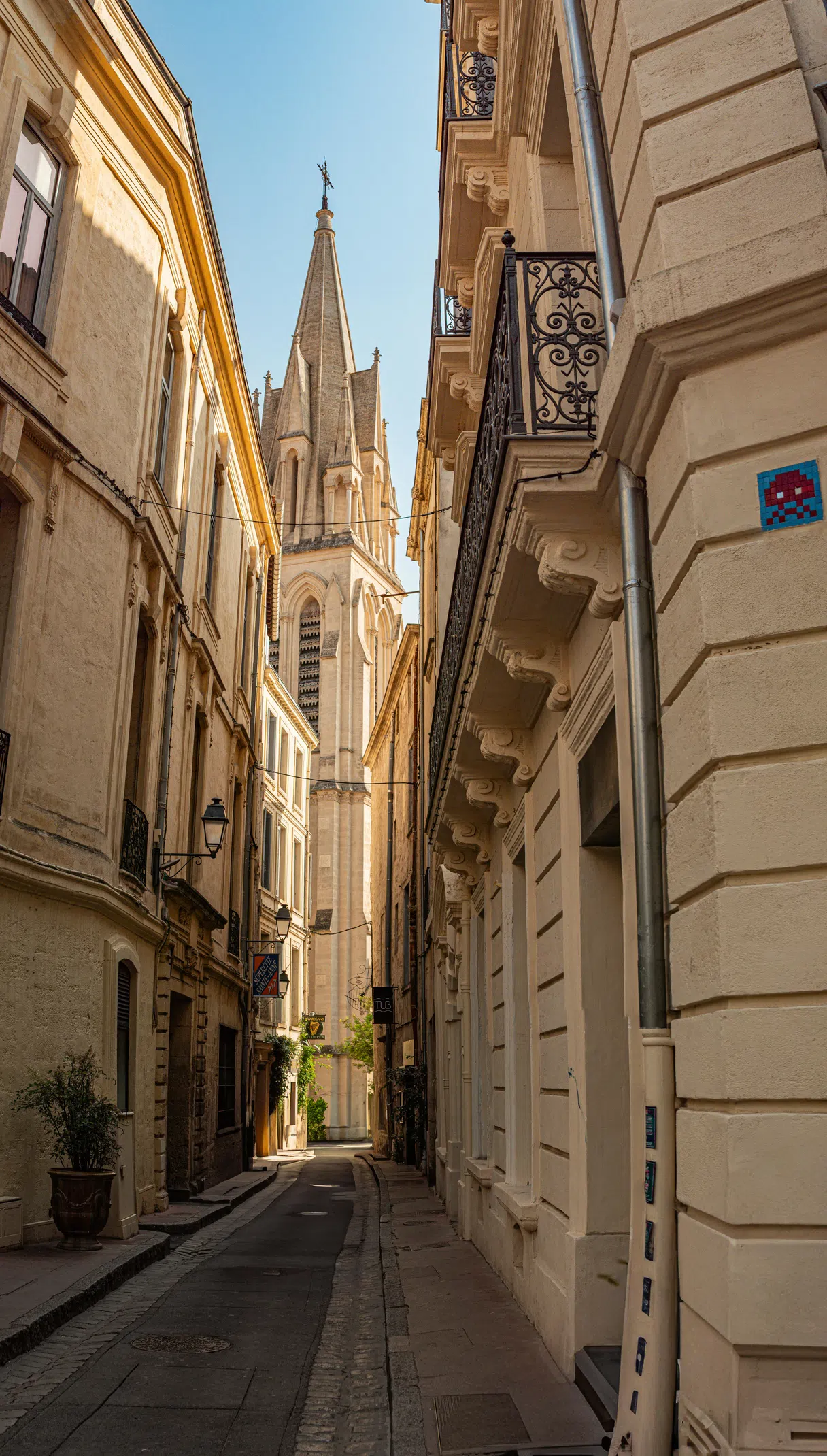 A narrow street in Montpellier’s historic center with a church tower above
