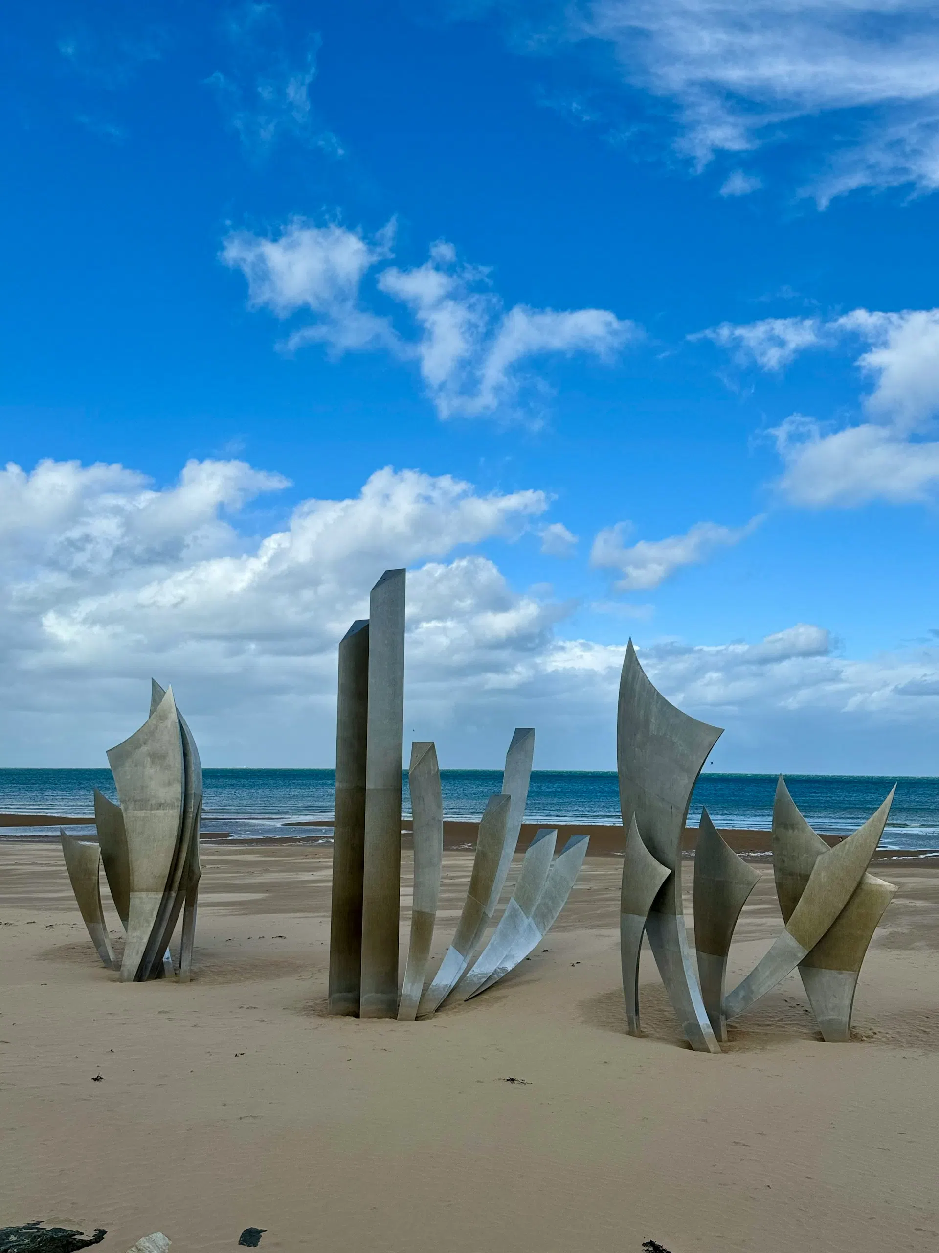 The Les Braves sculpture standing on the sand of Omaha Beach