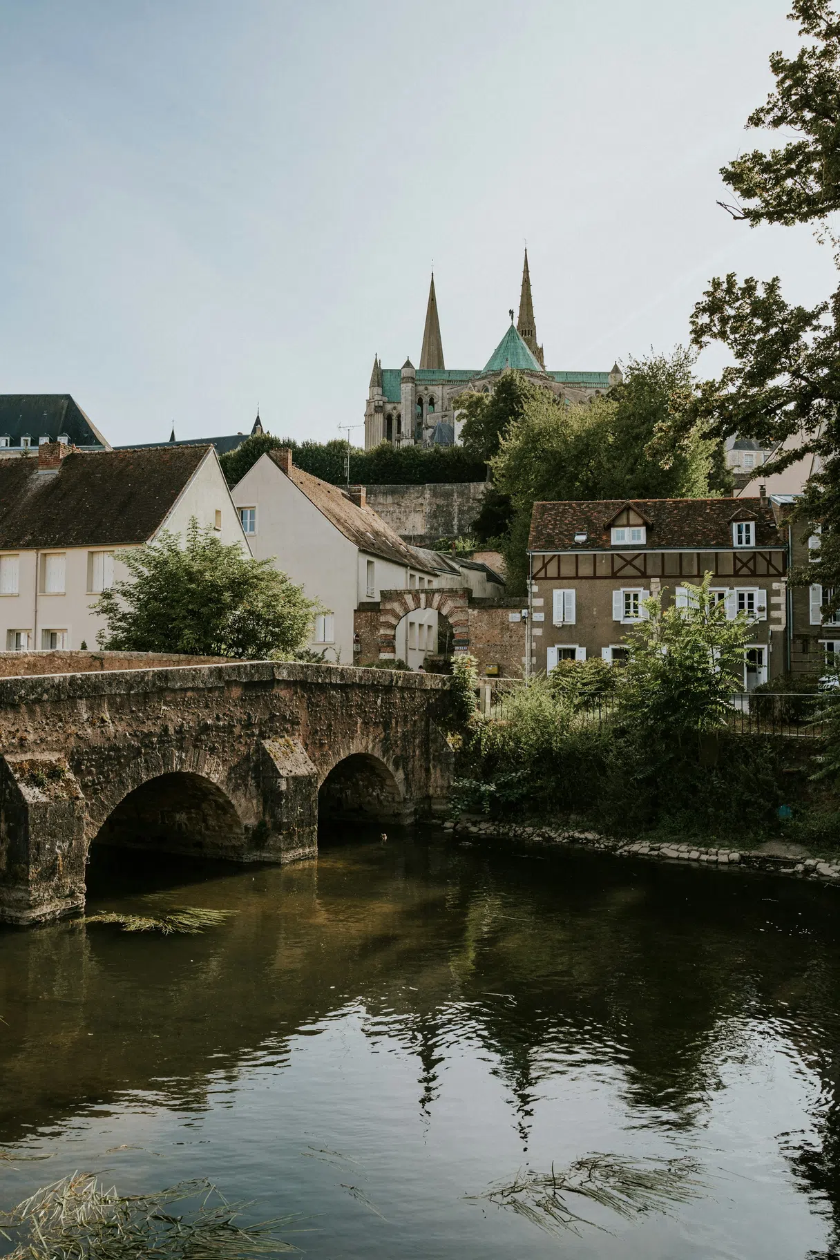 A stone bridge over the Eure with Chartres Cathedral rising above the town