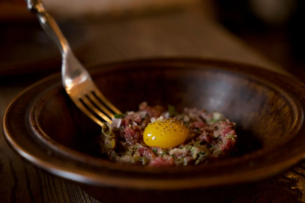 Steak tartare in a brasserie: seasoned raw beef served with egg yolk, capers, pickles and fries